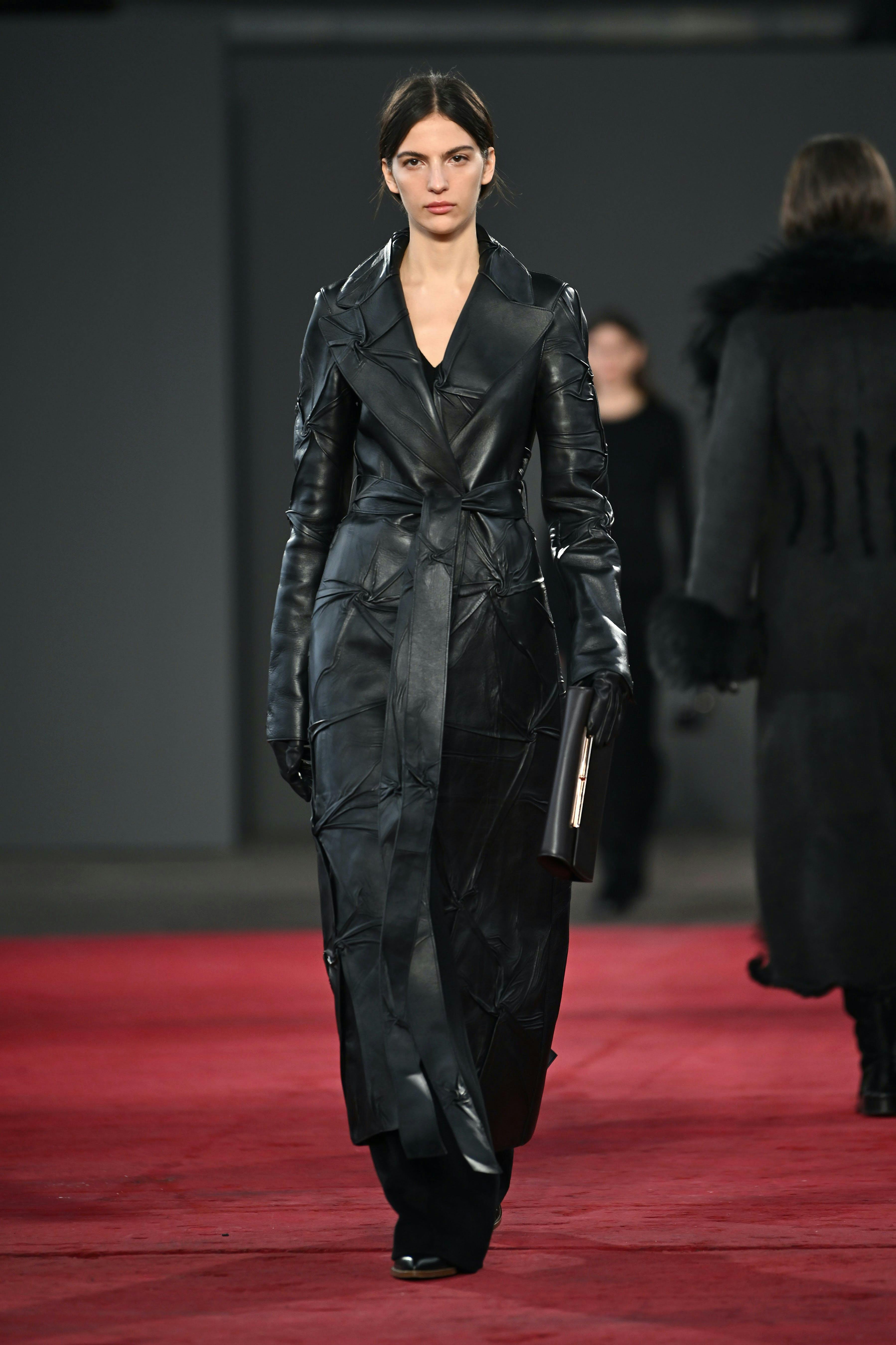 model on runway wearing black leather trench coat