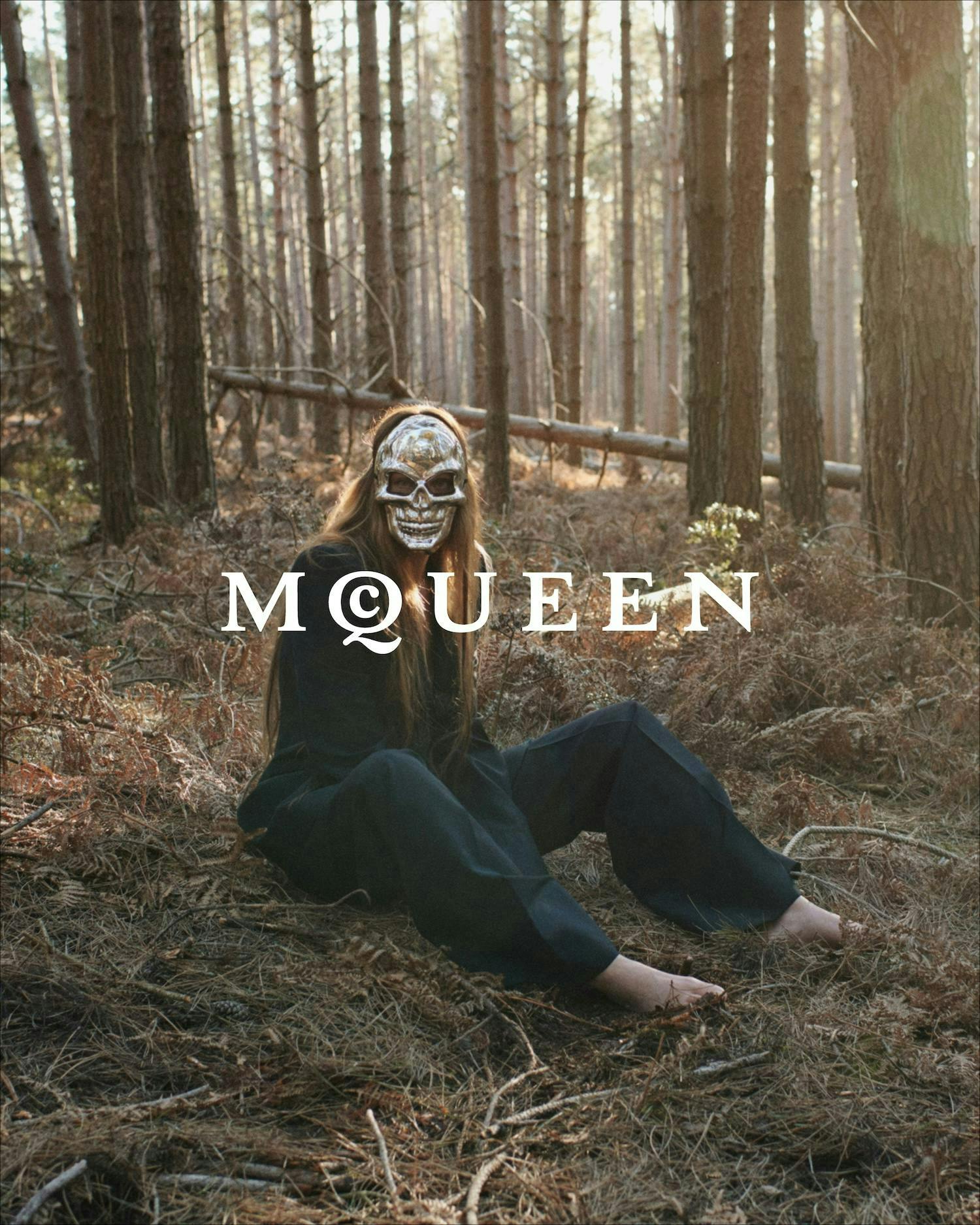 model sitting on ground wearing silver skull mask