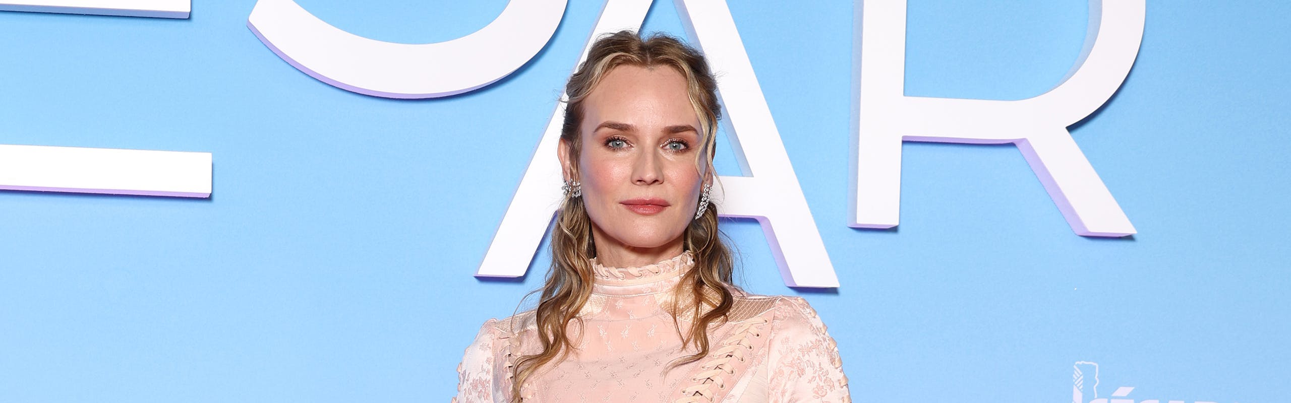 Diane Kruger in a pink high-neck long sleeve dress with a short hoop skirt lined with bows.
